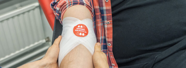 Blodgivarens armbågsbandage har en röd Lifesaver-dekal.